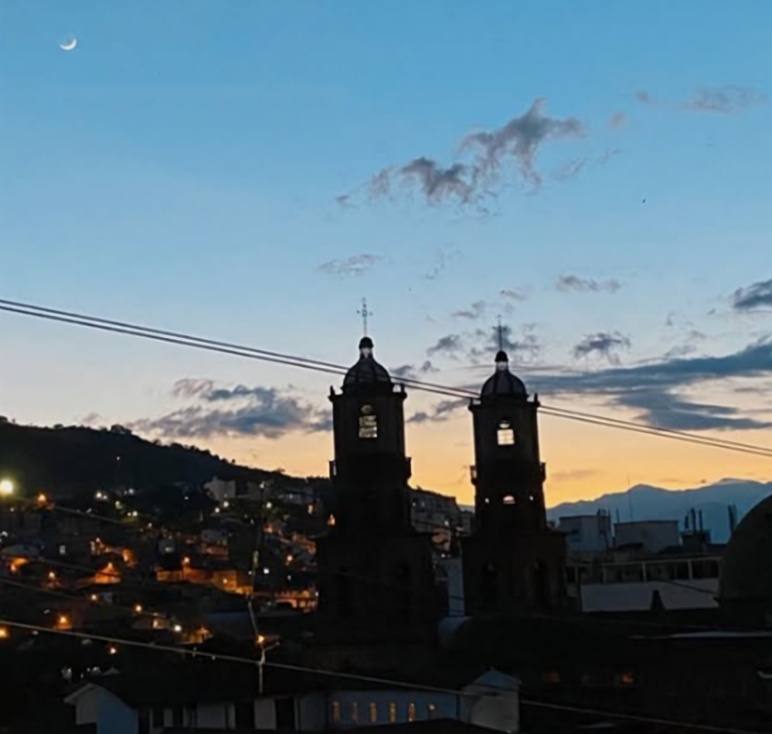 Hora azul sobre San Gil: las torres de la catedral en silueta, luces del pueblo y una luna creciente.